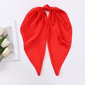 Close-up of a bright red silky satin scarf tied as a hair ribbon on a minimal white background