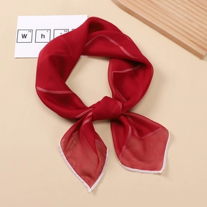 Close-up of red square silk scarf featuring delicate white rolled edges and wave patterns