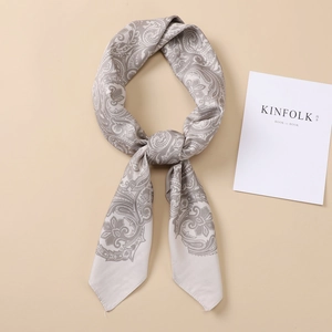 Silver-grey paisley satin silk square scarf styled in an elegant ring knot on plain background