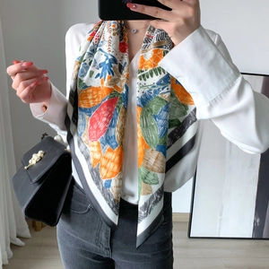 Écharpe en soie aux motifs de feuilles colorées et bordures noires sur une chemise blanche
