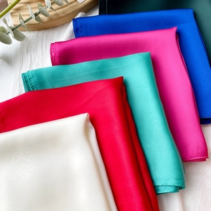 Detailansicht verschiedener einfarbiger Seidenschals mit eleganter Satin-Textur und Naht
