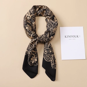 Macro detail of silk-like paisley pattern scarf in elegant black and beige golden tones