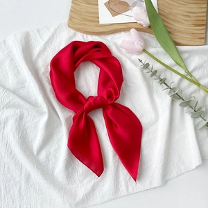 Eleganter leuchtend roter Satin-Viereckschal, stilvoll geknotet auf weichem Stoffhintergrund