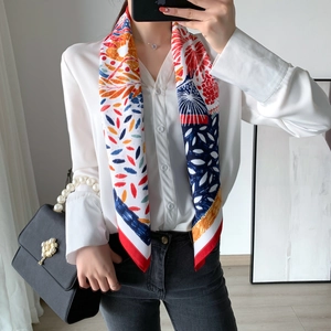 Foulard en soie coloré à motifs floraux porté avec un sac à main noir à poignée perle