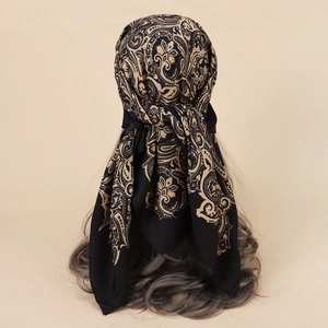 Detail showing a black and gold paisley satin headscarf styled on a fashion model
