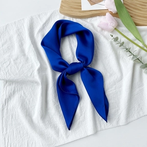Detail eines eleganten, knotengebundenen Seidenschals in Klein-Blau auf weißem Stoff