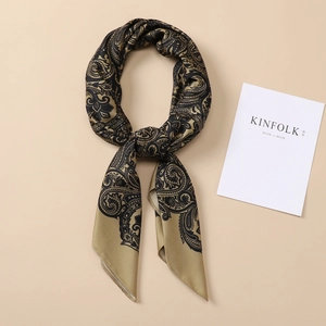 Close-up of golden and black paisley silk scarf with glossy satin texture and smooth edges