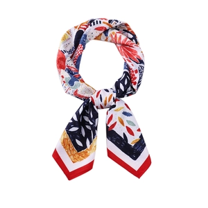 Détail d'un carré de soie imprimé avec des motifs abstraits colorés et des bords rouges