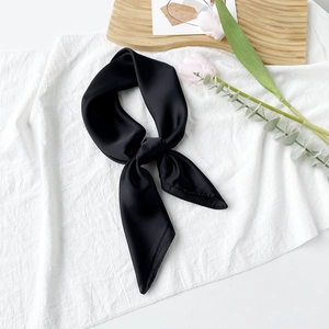 Detail eines geknoteten schwarzen Seidenschals mit Satin-Finish auf weißem Stoff