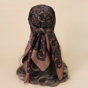 Detail of silk satin scarf with brown paisley floral pattern tied as a stylish headscarf
