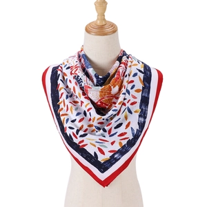 Détail d'un foulard en soie blanche avec motifs de feuilles et bordures rouges contrastées