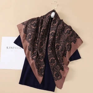 Close-up of coffee brown paisley silk scarf with vintage floral patterns on blue knitwear