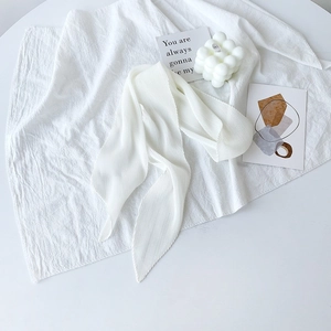 Dettaglio macro di una sciarpa in chiffon bianco a pieghe su sfondo minimalista