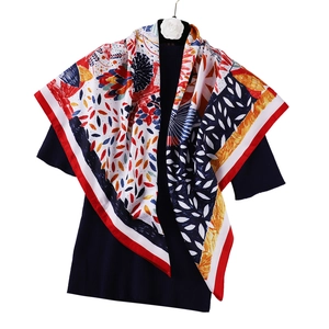 Détail d'un foulard carré aspect soie de 90 cm avec imprimé floral abstrait et bord rouge