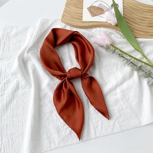 Detail eines eleganten karamellfarbenen Seidenschals mit glattem Satin-Finish und weichem Fall