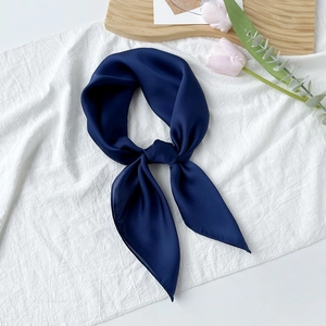 Detail eines marineblauen Satin-Vierecktuchs, als Schleife gebunden, auf weißem Grund