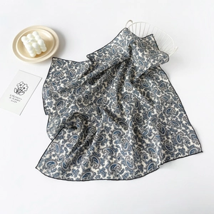 Close-up of blue paisley pattern on premium cotton square scarf with fine black rolled edges