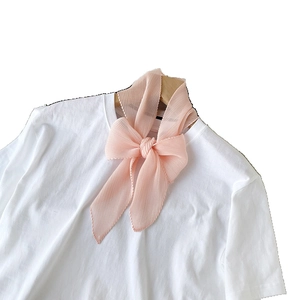 Sciarpa di seta plissettata rosa annodata a fiocco su t-shirt bianca, stile dolce