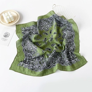 Detail of green cotton scarf with paisley pattern on white background showing fabric texture
