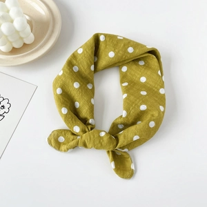 Close-up of mustard yellow cotton scarf with white polka dots and stylish knotted detail