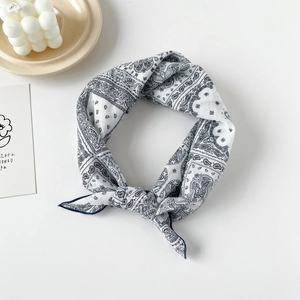 Close-up of navy blue paisley cotton square scarf tied neatly next to a candle