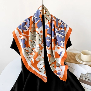 Carré de soie floral 90cm aux tons orange et bleu présenté élégamment sur un support