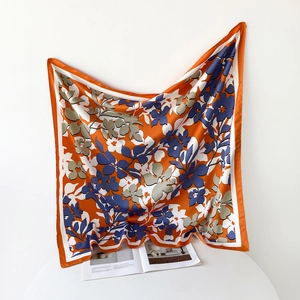 Détail d'un grand carré de soie orange aux motifs floraux élégants et légers