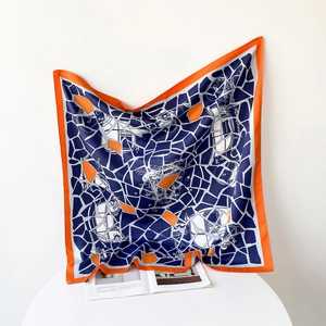 Detail of light twill silk scarf showing orange borders and navy geometric patchwork patterns