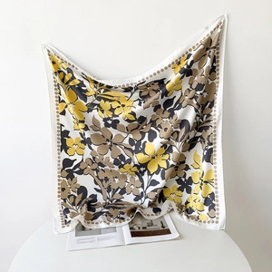 Détail de l'imprimé floral sur un foulard carré soyeux aux tons jaune et marron