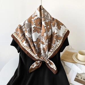 Vue détaillée d'un foulard en soie à fleurs élégamment drapé sur une robe noire