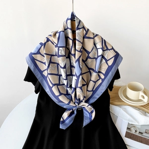 Detail view of blue and beige geometric pattern silk scarf styled on a black dress