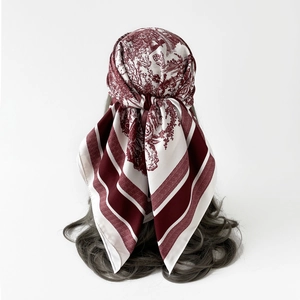 Detail view of burgundy Toile de Jouy silk scarf tied elegantly on long wavy hair back