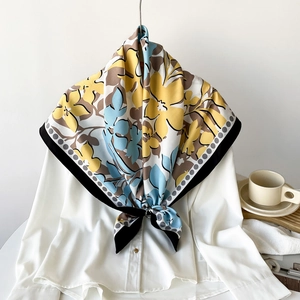 Foulard en soie noué avec motifs floraux jaunes et bleus sur une chemise blanche