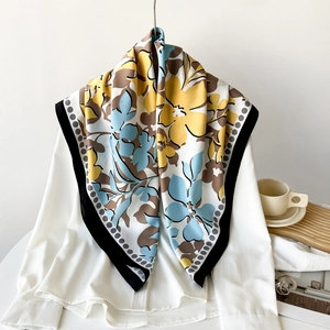 Détail d'un foulard en satin à motif floral avec chemise blanche et tasse de café