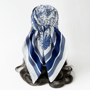 Detail of silk-like square scarf featuring blue Toile de Jouy pattern on white silk fabric