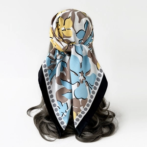 Vue détaillée d'un foulard carré en soie à motifs floraux bleus et jaunes porté en bandana