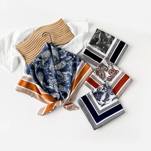 Detail of assorted silk square scarves with paisley patterns on a wooden tray