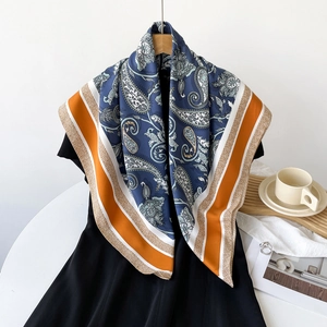 Detail shot of vintage paisley pattern silk scarf with blue and orange border on black dress