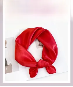 Detail of red satin neck scarf with silky finish tied on a stylish magazine