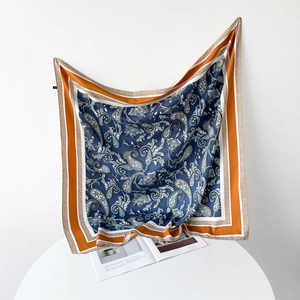 Detail of elegant navy and orange paisley silk scarf draped with smooth texture and luxury shine