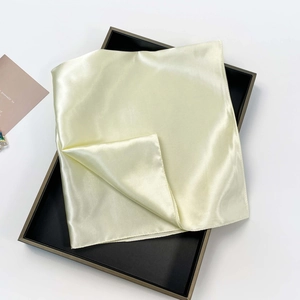 Close-up of cream white satin silk scarf with pearlescent texture on a display tray