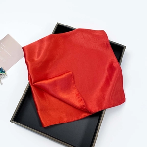 Detail of red satin scarf with premium smooth texture in elegant black gift box