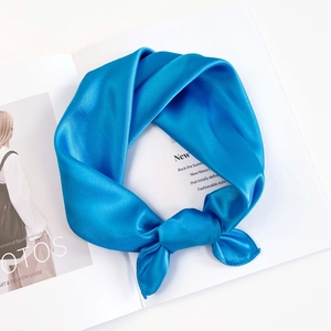Detail of bright blue silk-like square scarf tied in a knot on a fashion magazine