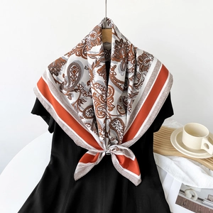 Close-up of retro paisley silk scarf with orange borders on a wooden hanger with props