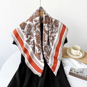 Detail of white silk scarf with brown paisley pattern draped over a black dress