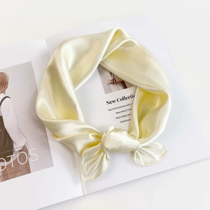 Detailed view of apricot satin silk scarf with elegant knot on a fashion magazine