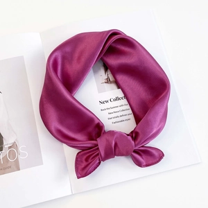 Close-up of knotted dark violet silk-like satin square scarf on an English magazine