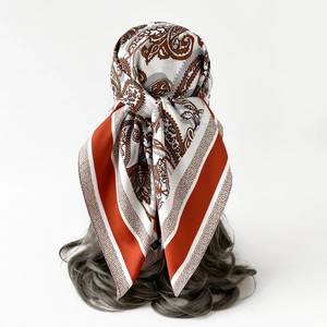 Detail of vintage paisley pattern square scarf tied on hair showing soft silk texture