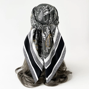 Classic paisley silk scarf tied as a headband on dark grey hair against white backdrop