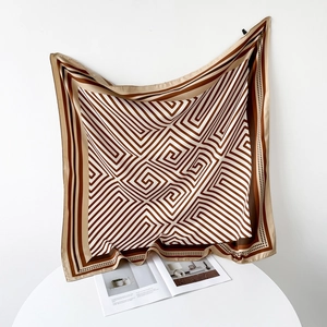Detail of elegant silk square scarf with geometric pattern and stripes on a white table